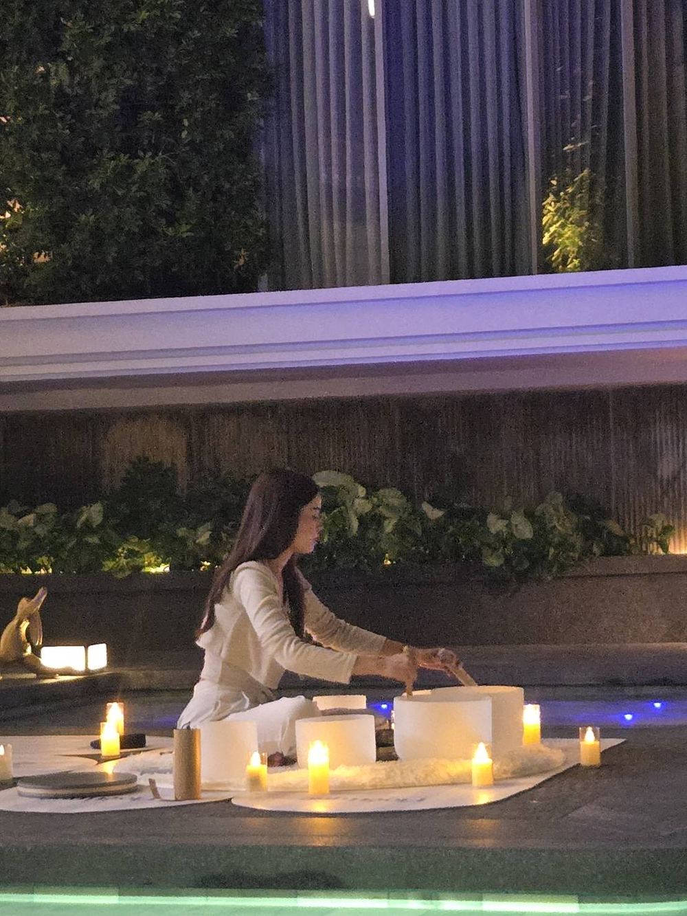 A facilitator playing crystal singing bowls at the edge of a floating sound bath