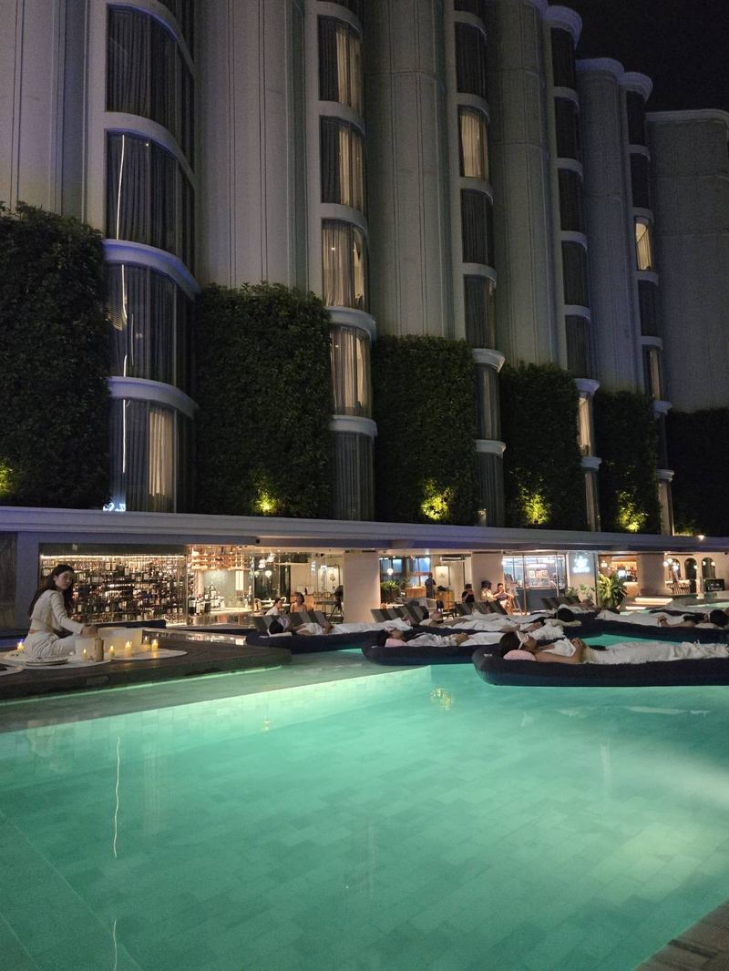 A hotel pool lit for an evening poolside wellness experience