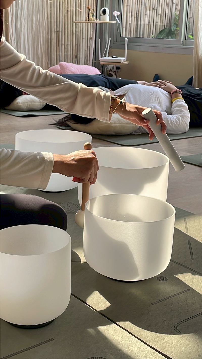 A facilitator holding a singing bowl over a guest during a private sound healing session