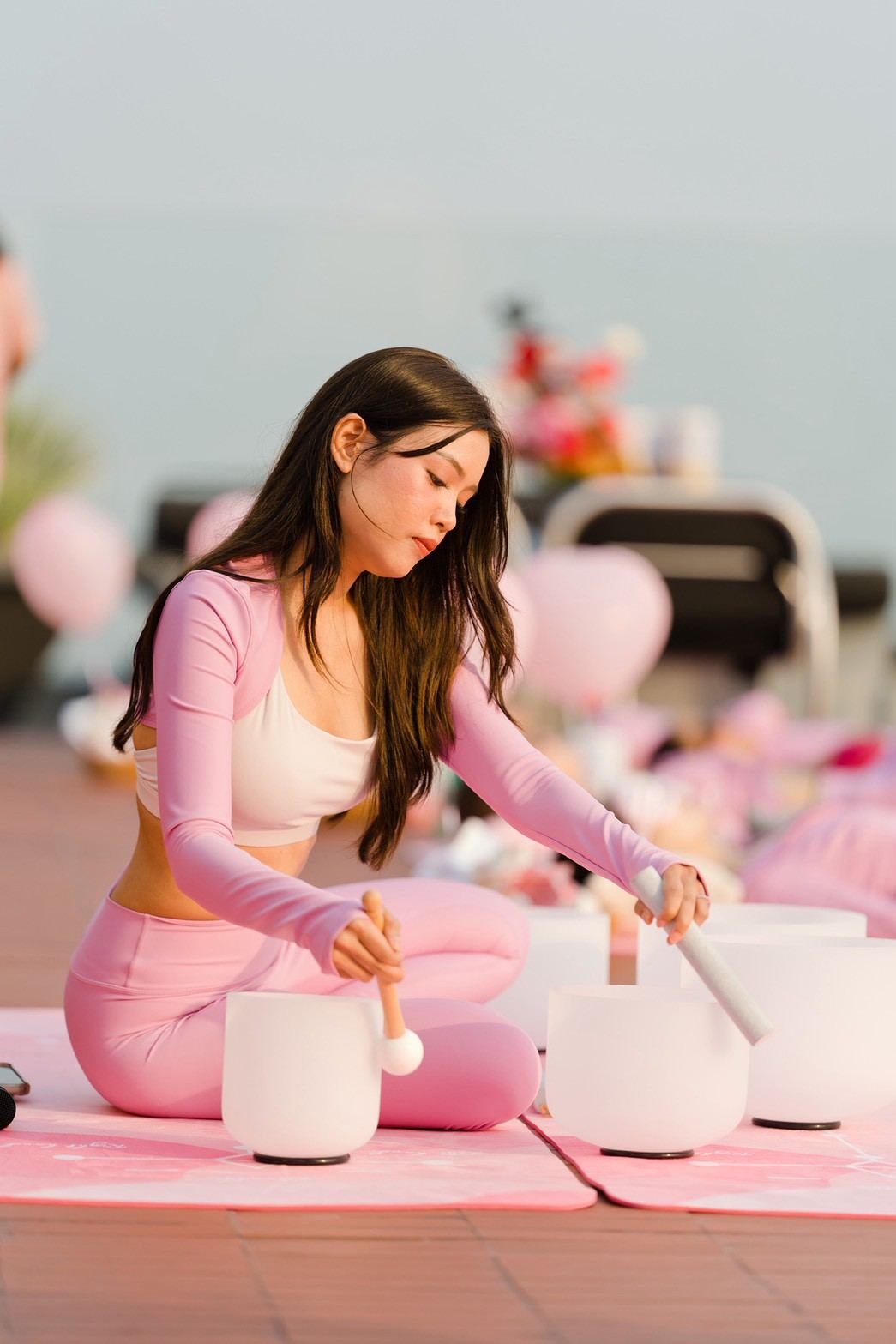 A Salty Dog Retreats facilitator playing a crystal singing bowl at a rooftop sound bath in Bangkok